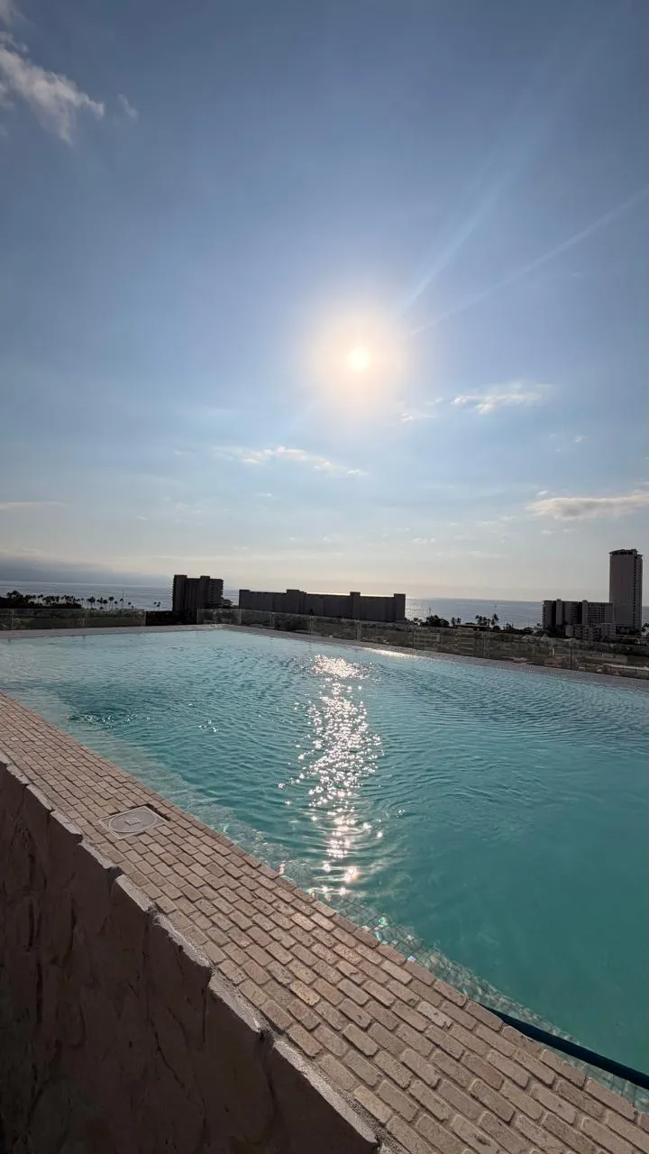 Alberca de azotea a contraluz con los hoteles al fondo