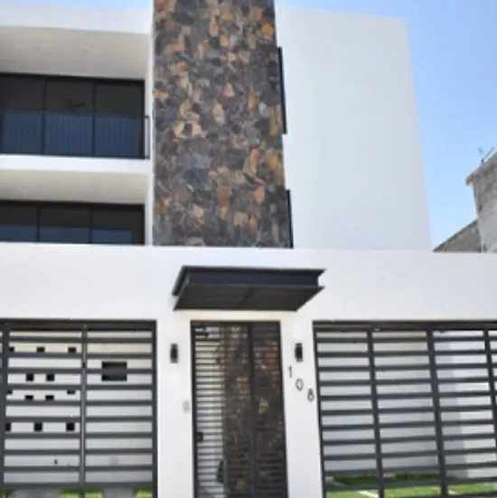 Fachada blanca con columna de piedra y portones de herrería