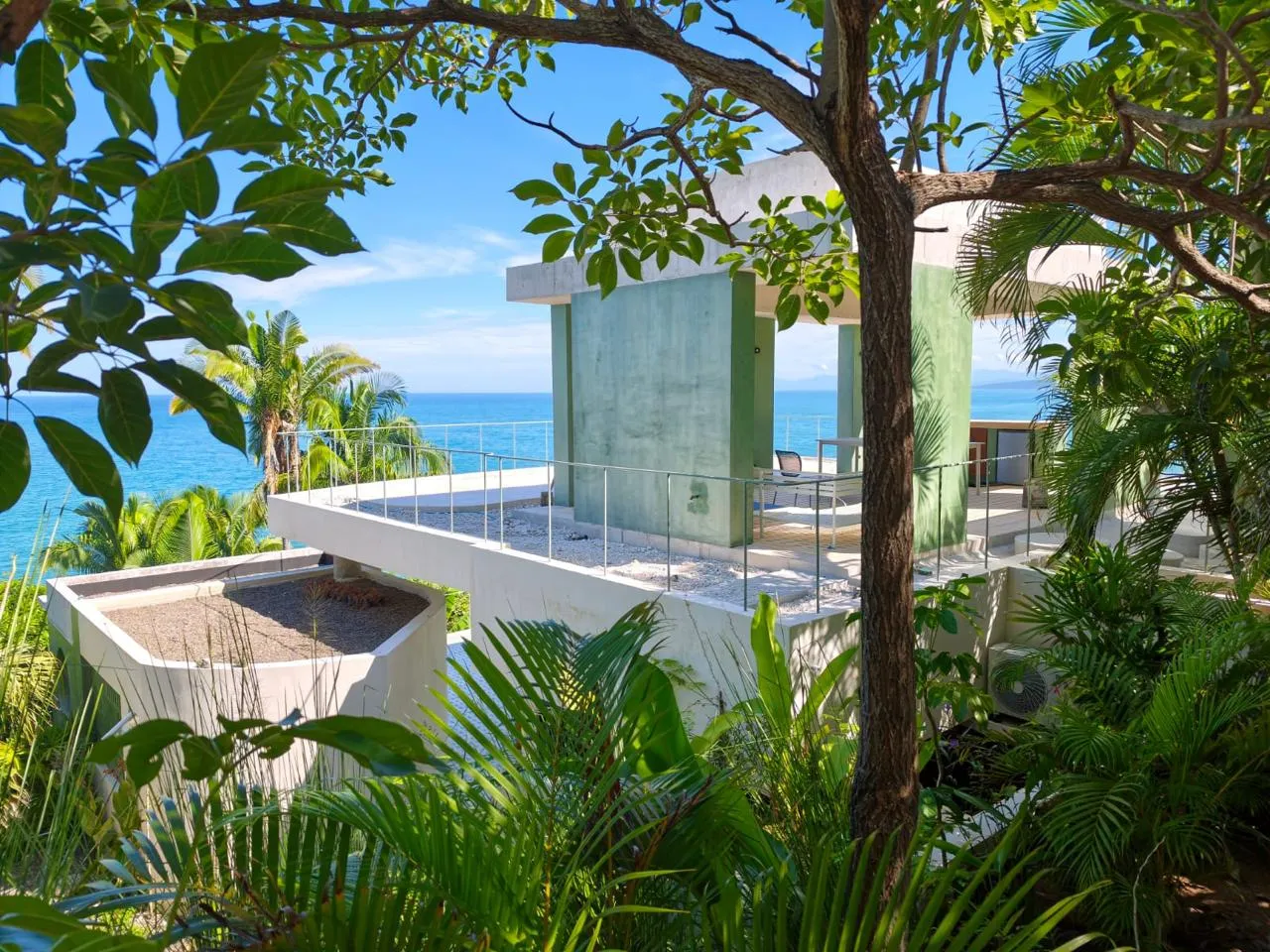 Casa de concreto verde entre la selva con vista al mar