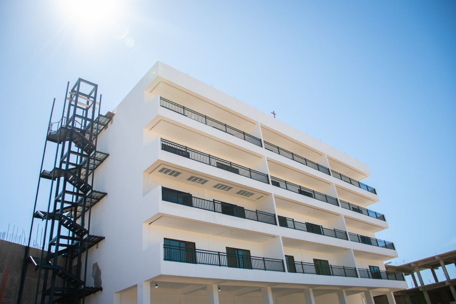 Edificio blanco de cinco niveles con escalera metálica exterior